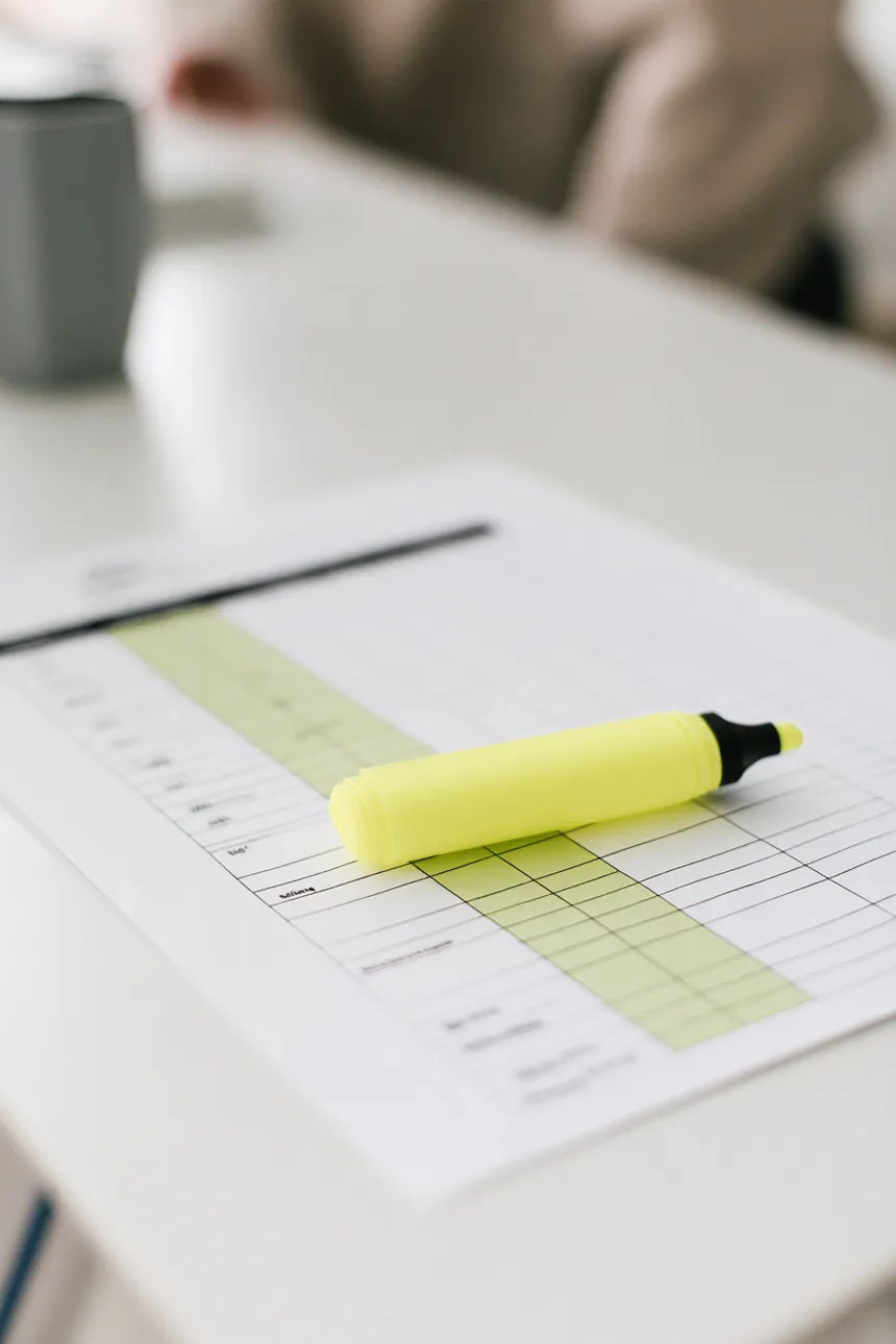 Flat lay of a printed comparison chart with a highlighter on a white desk